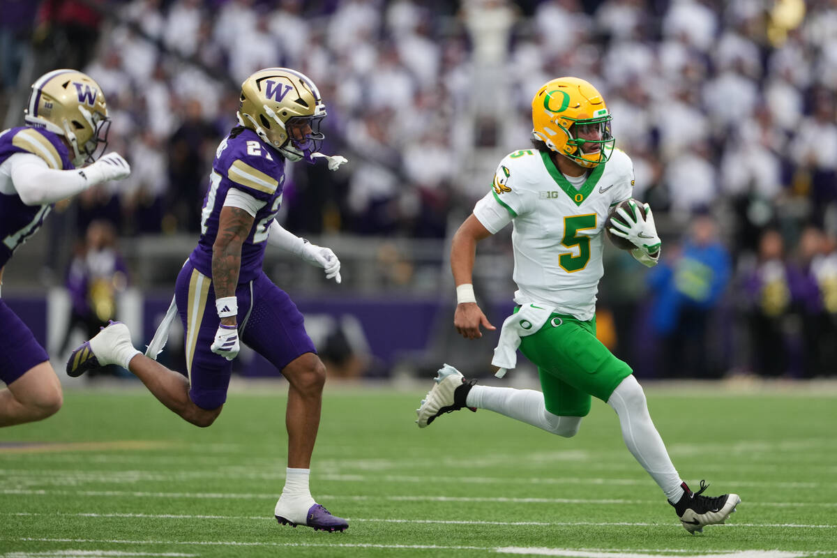 Oregon quarterback Dante Moore (5) runs the ball against Washington safety Vincent Holmes durin ...