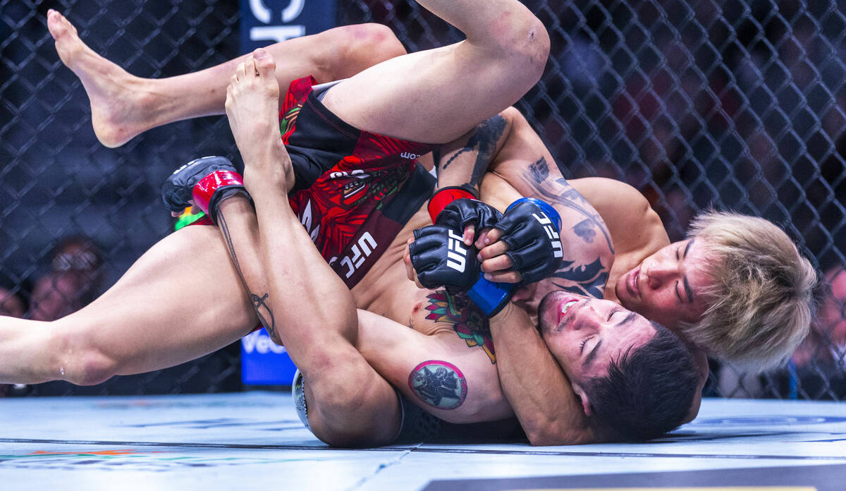 Brandon Moreno is wrapped up from behind by Tatsuro Taira during their flyweight fight in UFC 3 ...