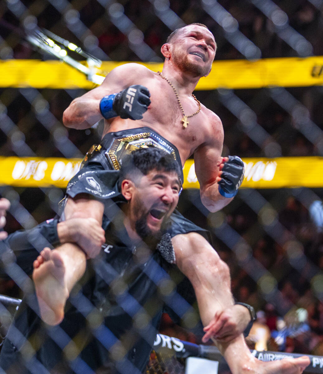 Petr Yan is carried about the octagon with his new belt after defeating Merab Dvalishvili durin ...