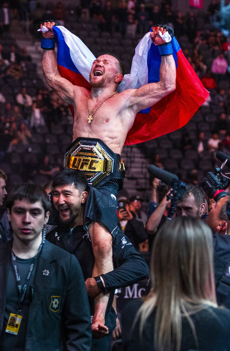 Petr Yan is carried from the octagon with his new belt after defeating Merab Dvalishvili during ...