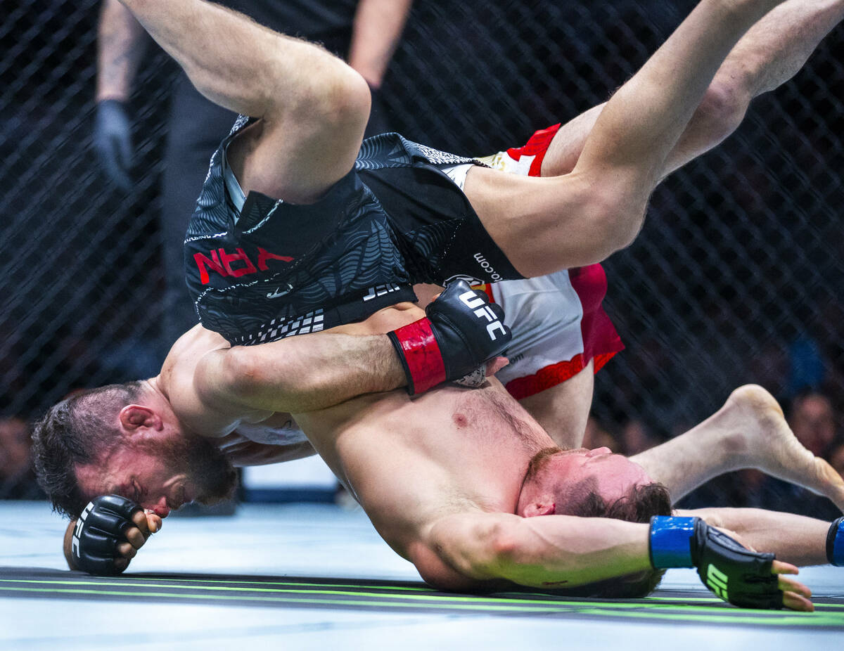 Merab Dvalishvili and Petr Yan topple each other on the canvas during their bantamweight title ...