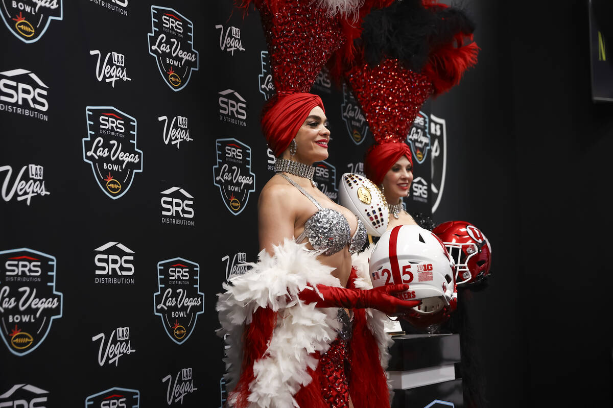 Showgirls Porsha Revesz, left, and Jenn Autry pose with football helmets from Nebraska and Utah ...