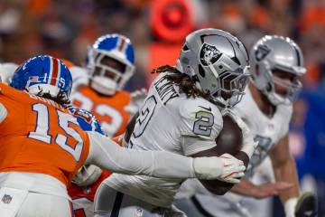 Raiders running back Ashton Jeanty (2) slips by Denver Broncos linebacker Nik Bonitto (15) duri ...