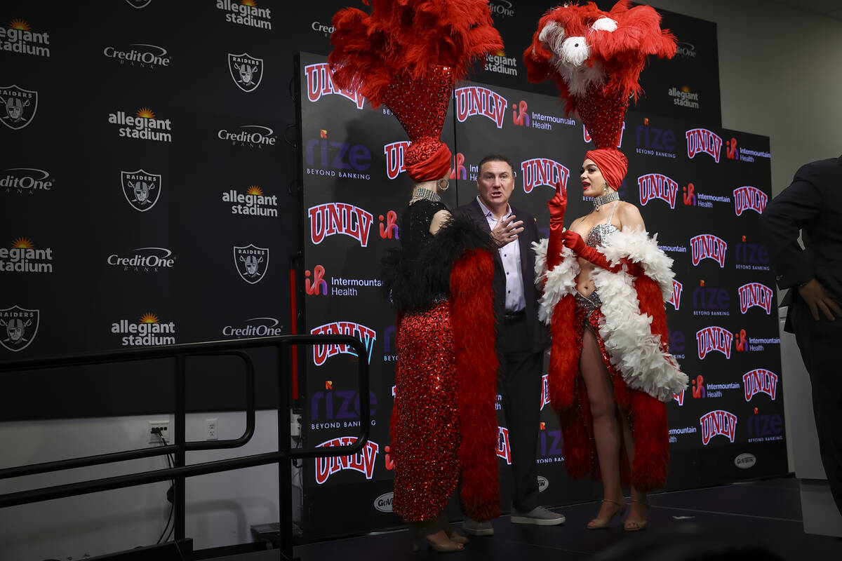 UNLV football coach Dan Mullen talks with showgirls Porsha Revesz, right, and Jenn Autry, left, ...