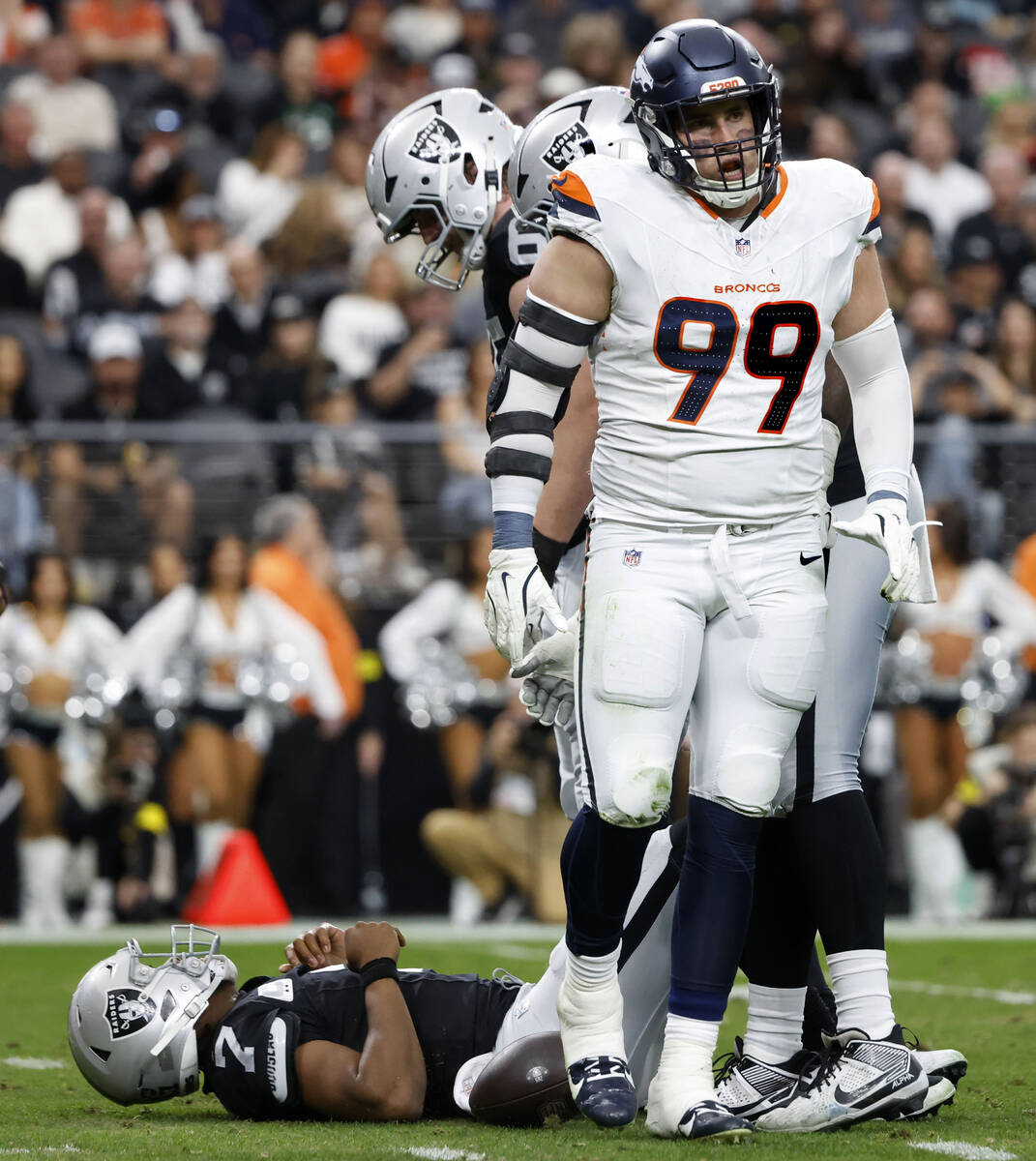 Raiders quarterback Geno Smith (7) lies on the ground after being sacked by Denver Broncos defe ...