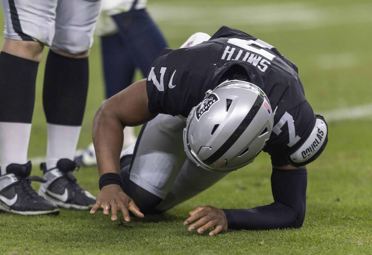 Raiders quarterback Geno Smith (7) struggles to get up after being hit as he examines his right ...