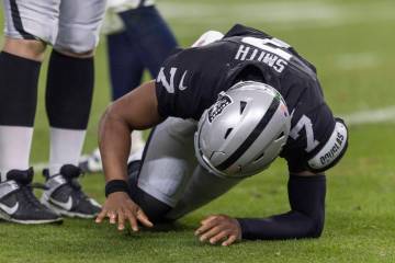 Raiders quarterback Geno Smith (7) struggles to get up after being hit as he examines his right ...