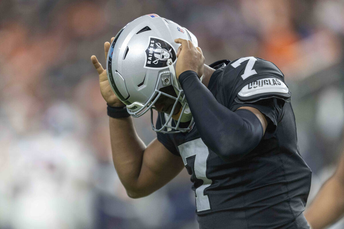 Raiders quarterback Geno Smith (7) heads back to the sideline struggling to remove his helmet a ...