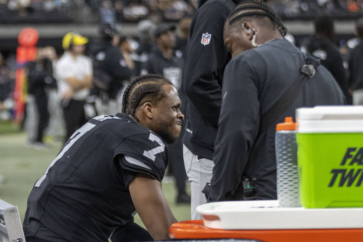 Raiders quarterback Geno Smith (7) gets his hand injury looked at on the sideline during the se ...