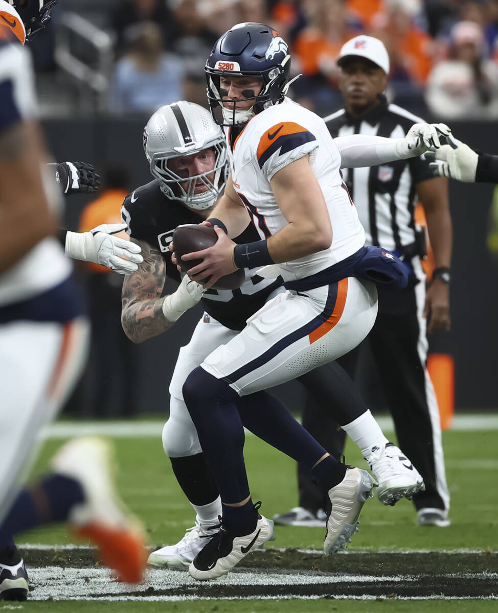 Denver Broncos quarterback Bo Nix (10) tries to get away from Raiders defensive end Maxx Crosby ...