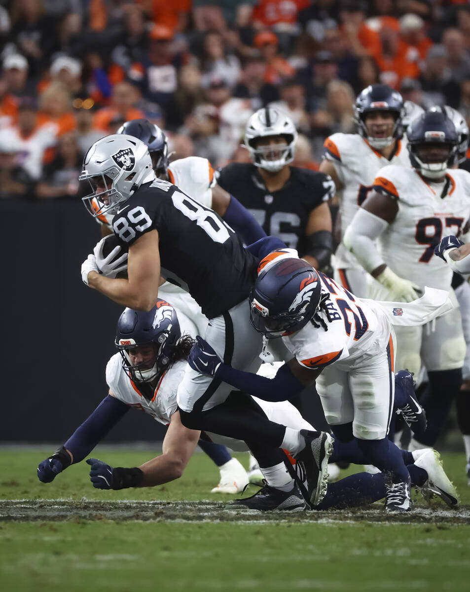Raiders tight end Brock Bowers (89) gets tackled by Denver Broncos cornerback Jahdae Barron (23 ...