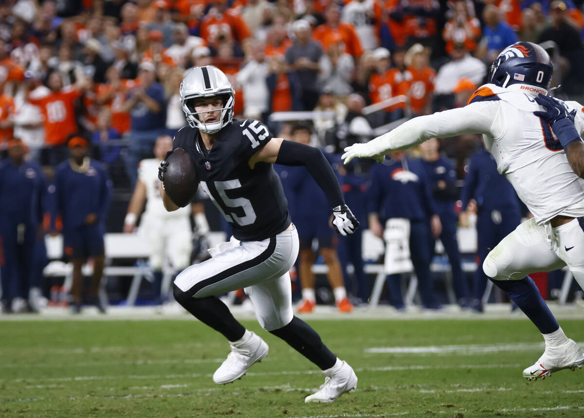 Raiders quarterback Kenny Pickett (15) runs the ball under pressure from Denver Broncos Jonatho ...