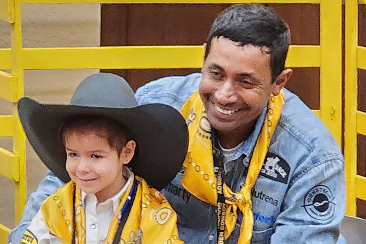 World champion team roper Junior Nogueira shares his hat with a child during Saturday's Golden ...