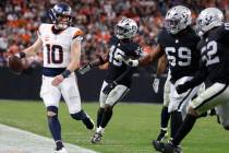 Denver Broncos quarterback Bo Nix (10) is chased by a trio of Raiders defenders during the seco ...