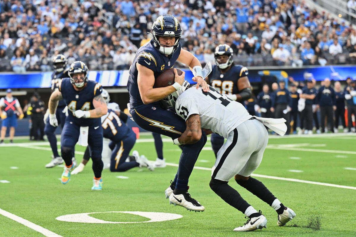 Los Angeles Chargers quarterback Justin Herbert (10) is tackled by Las Vegas Raiders safety Jer ...