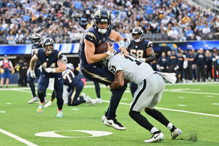 Los Angeles Chargers quarterback Justin Herbert (10) is tackled by Las Vegas Raiders safety Jer ...