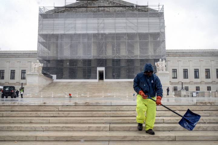 A worker shovels snow and ice in front of the Supreme Court building during the first snowfall ...