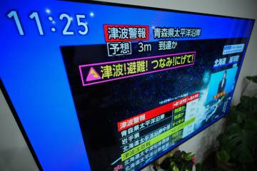 A tsunami warning is displayed on a television in Yokohama, near Tokyo, Monday, Dec. 8, 2025, a ...