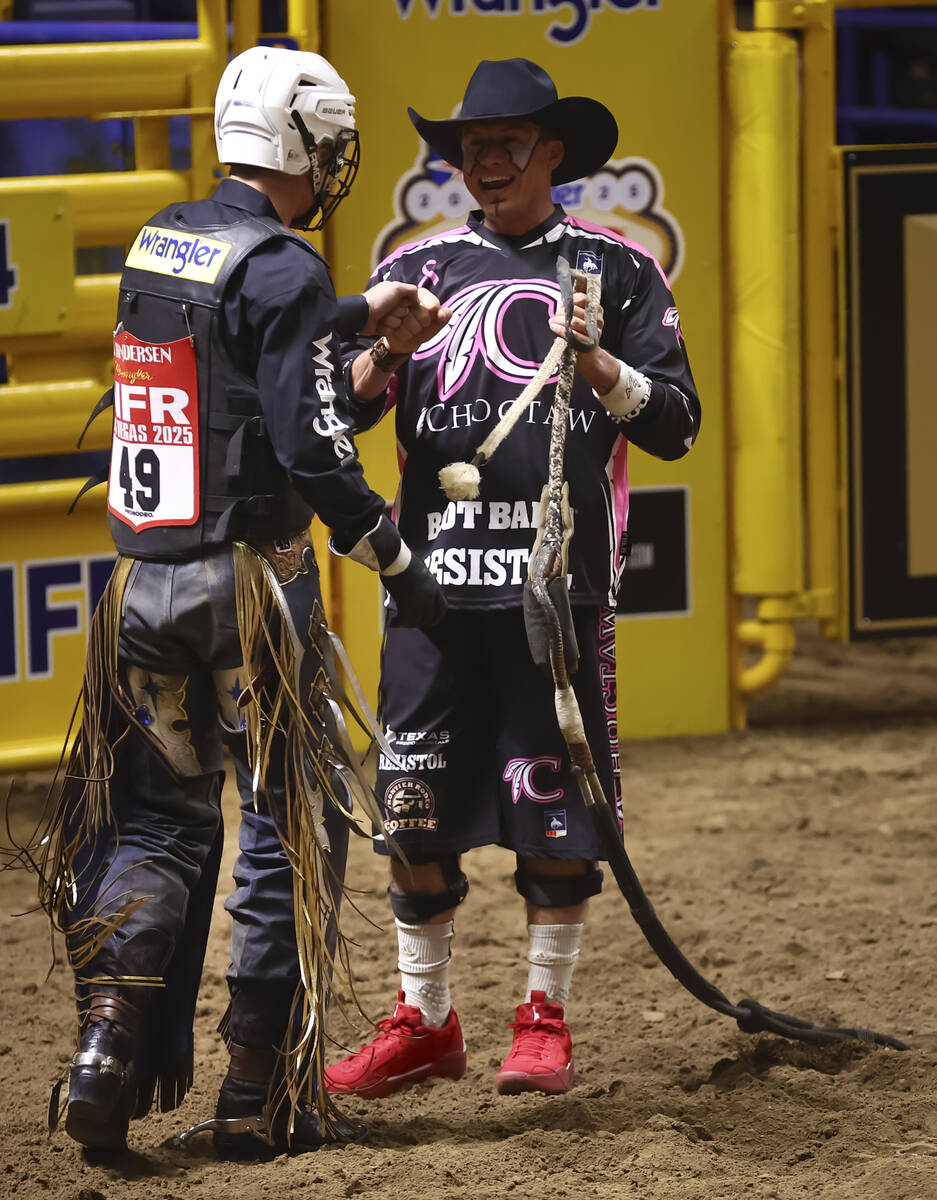 Bullfighter Cody Webster, right, fist bumps Qynn Andersen during the fifth go-round of the Nati ...