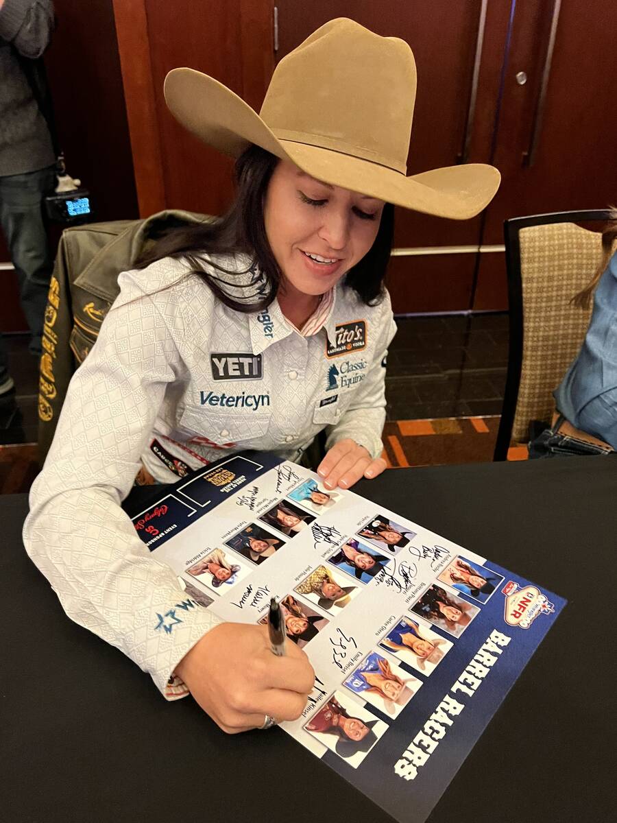 Four-time world champion Hailey Kinsel signs a poster for a fan during Friday's barrel racing a ...