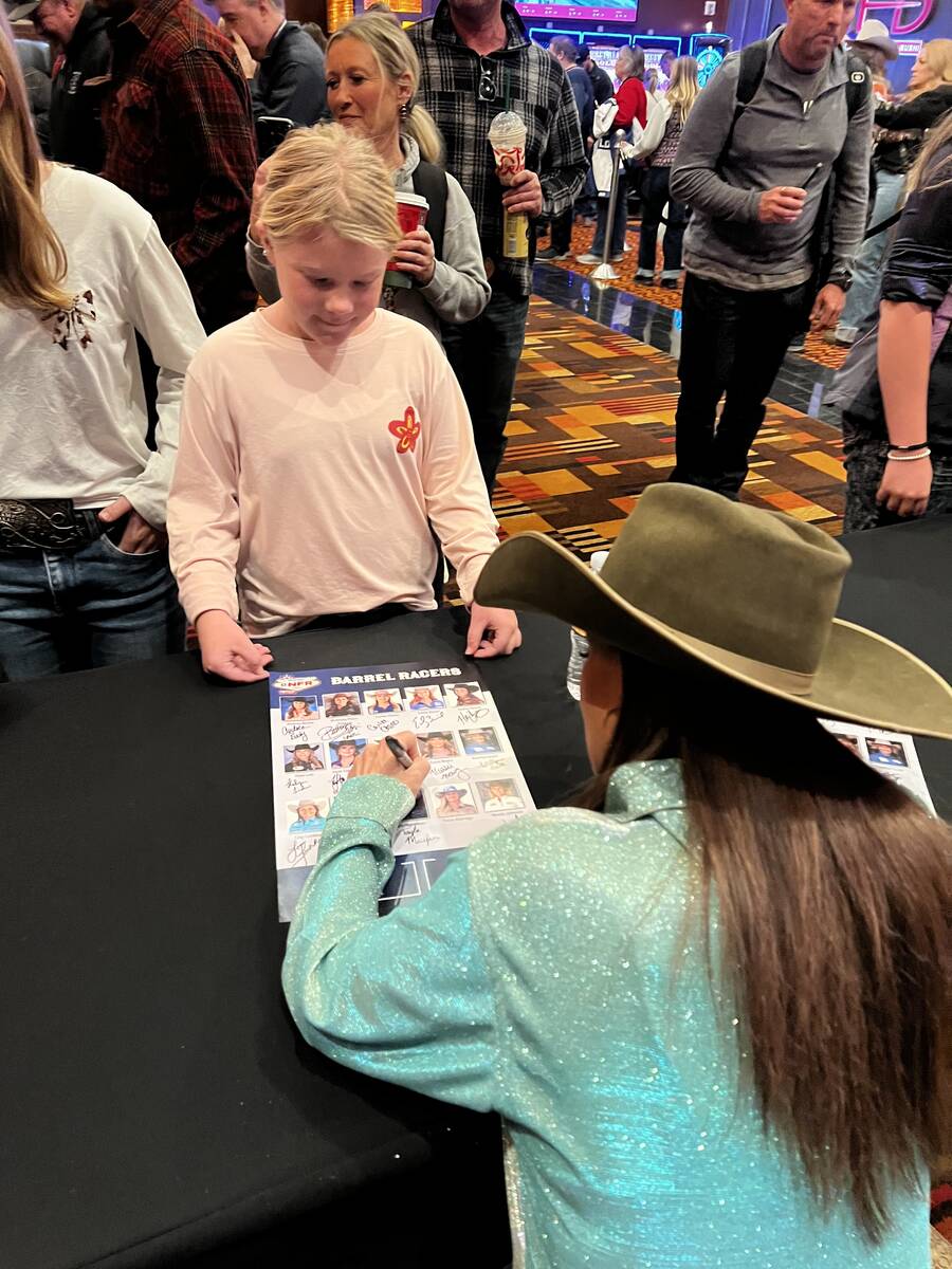 Barrel racer Julie Plourde signs a poster for young fan Jensyn Speck of Throckmorton, Texas, du ...