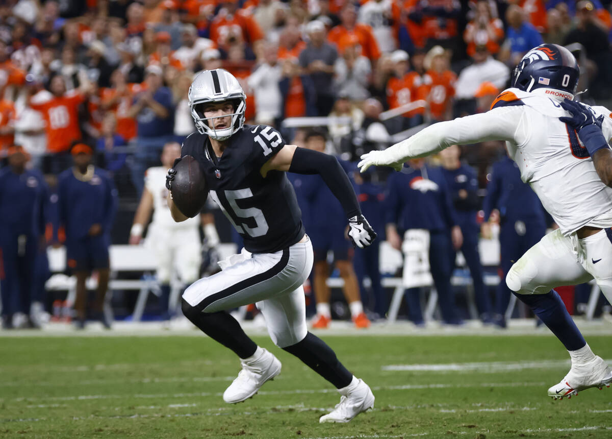 Raiders quarterback Kenny Pickett (15) runs the ball under pressure from Denver Broncos Jonatho ...