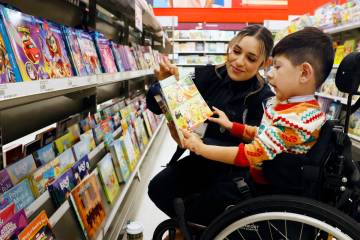 North Las Vegas police detective D. Franco and Aiden Alcantar, 4, check out children's books du ...