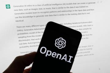 FILE - The OpenAI logo is seen on a mobile phone in front of a computer screen displaying outpu ...