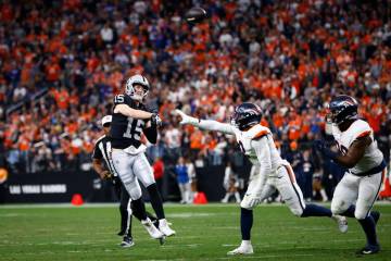 Raiders quarterback Kenny Pickett (15) throws a pass under pressure from Denver Broncos Jonatho ...