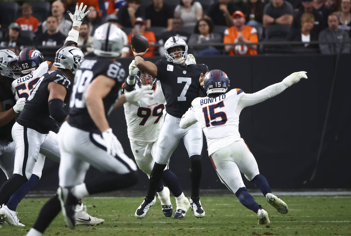Raiders quarterback Geno Smith (7) throws a pass under pressure from Denver Broncos defensive e ...