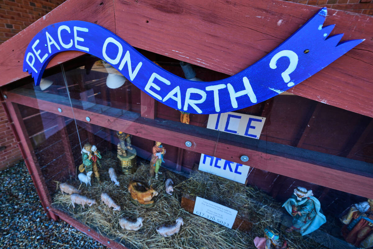 A "PEACE ON EARTH?" sign is posted on the top of a nativity display, which features a ...