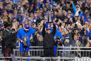Boise State head coach Spencer Danielson, center, holds up the trophy after defeating UNLV in ...