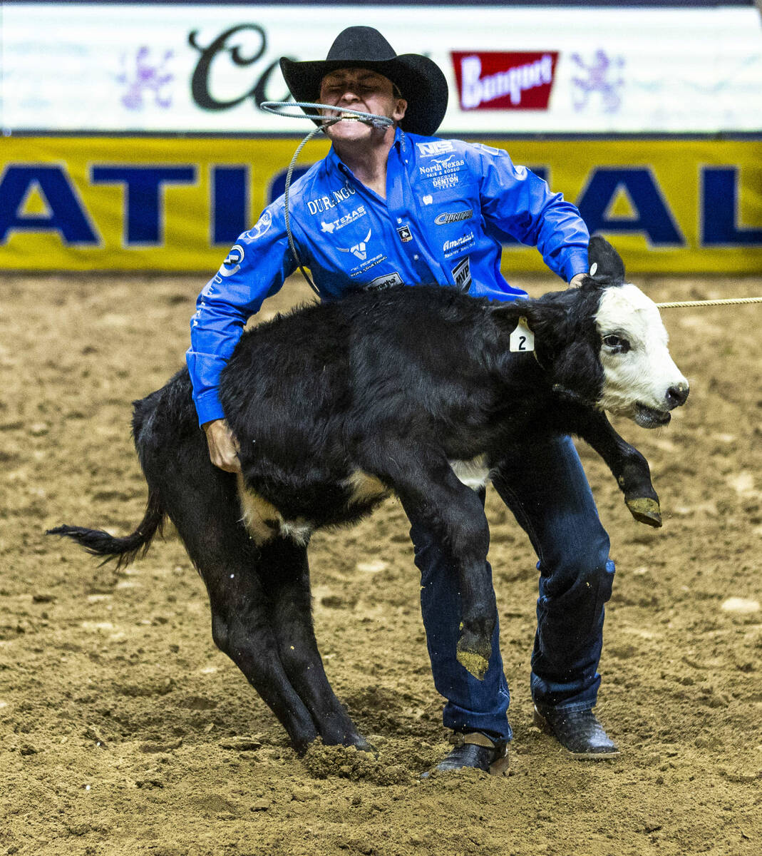 Riley Webb lifts his calf for the fastest time in Tie-Down Roping during the 9th go-round of Na ...