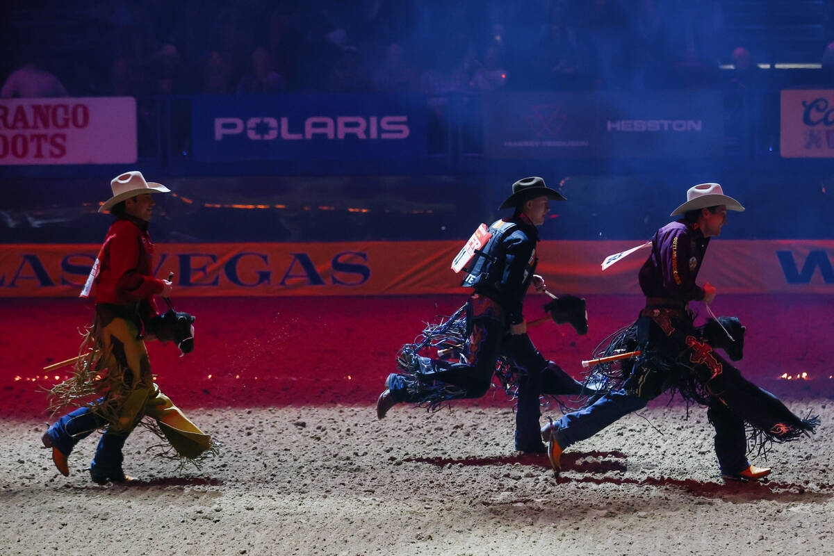 Bull riding contestants run out for their introduction while riding wooden horses in the 10th g ...