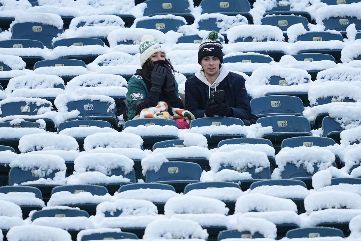 Fans of the Philadelphia Eagles sit in seats surrounded by snow before an NFL football game bet ...