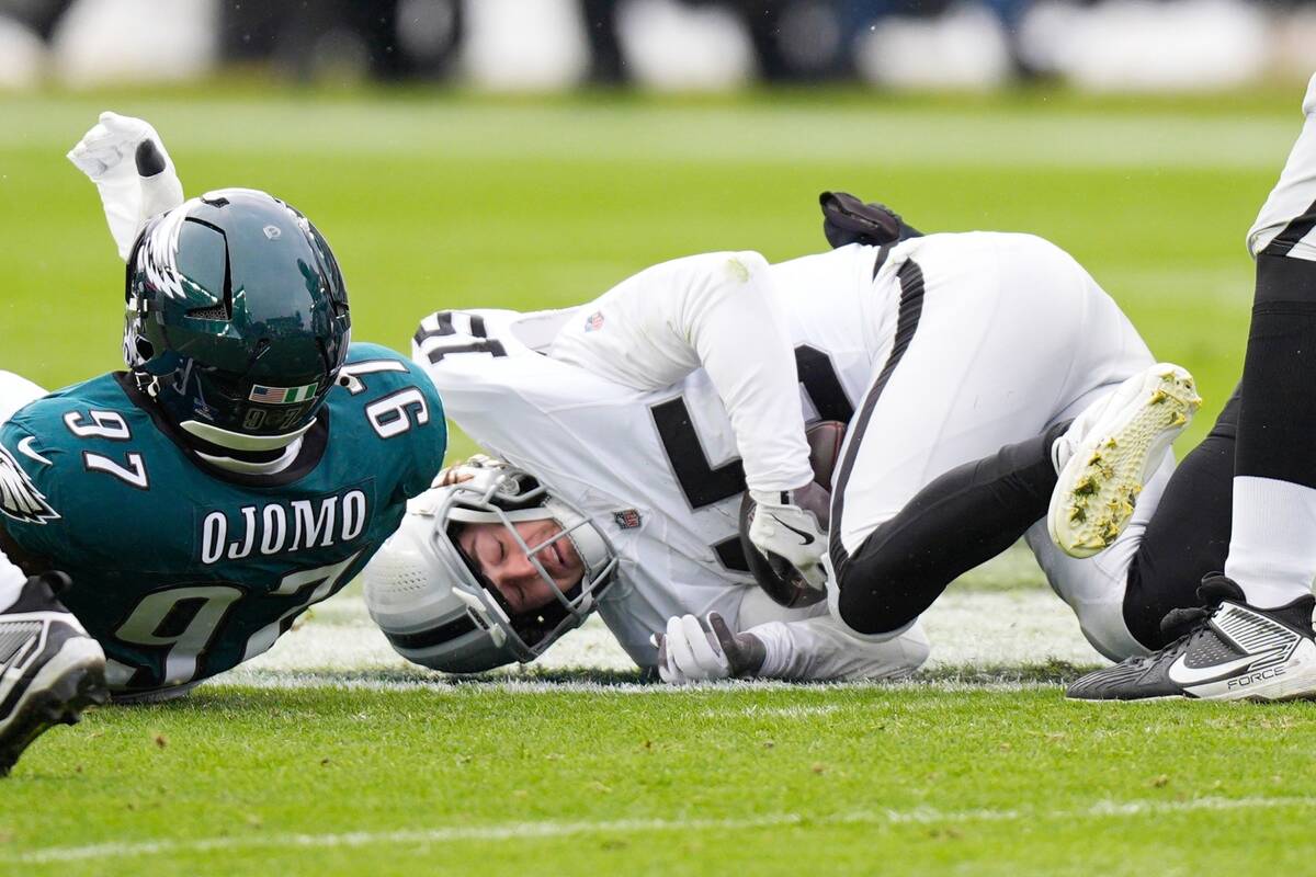 Las Vegas Raiders quarterback Kenny Pickett (15) is stacked by Philadelphia Eagles defensive ta ...
