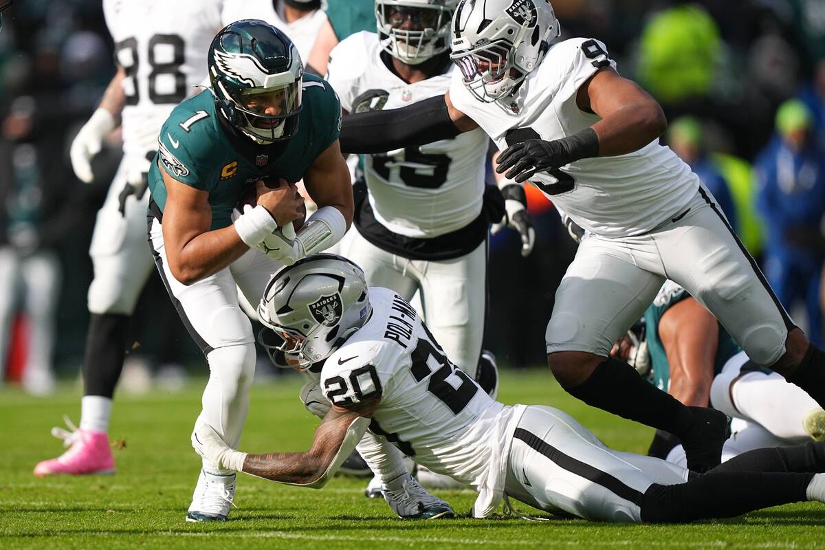 Philadelphia Eagles quarterback Jalen Hurts (1) is brought down by Las Vegas Raiders safety Isa ...