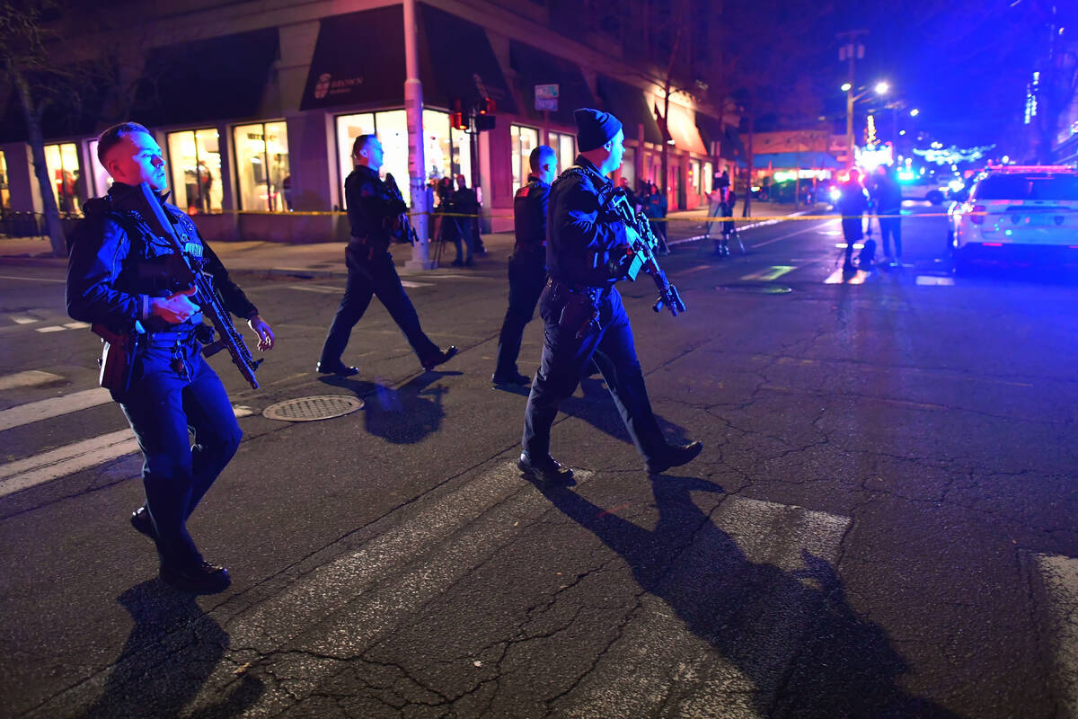 Law enforcement officials carry rifles while walking on a street in a neighborhood near Brown U ...