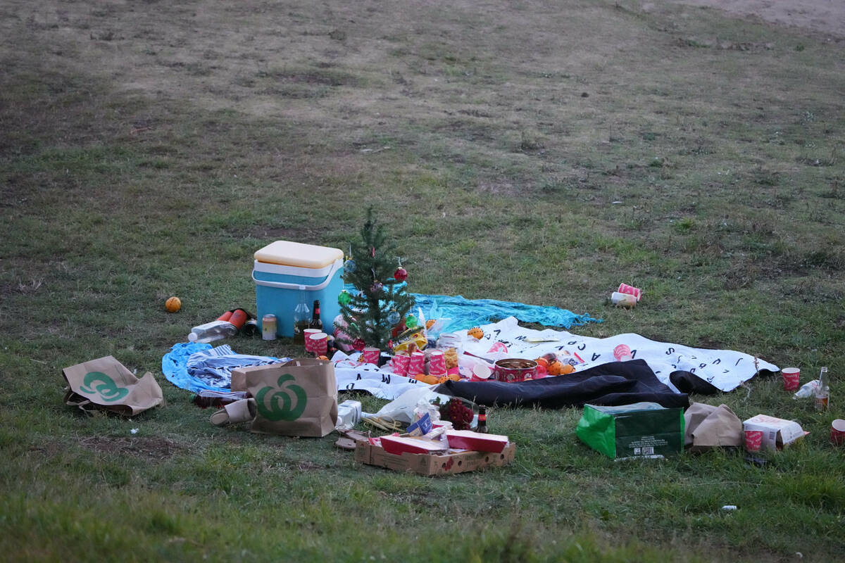 A small Christmas tree is at the center of an abandoned holiday picnic at Bondi Beach after a r ...