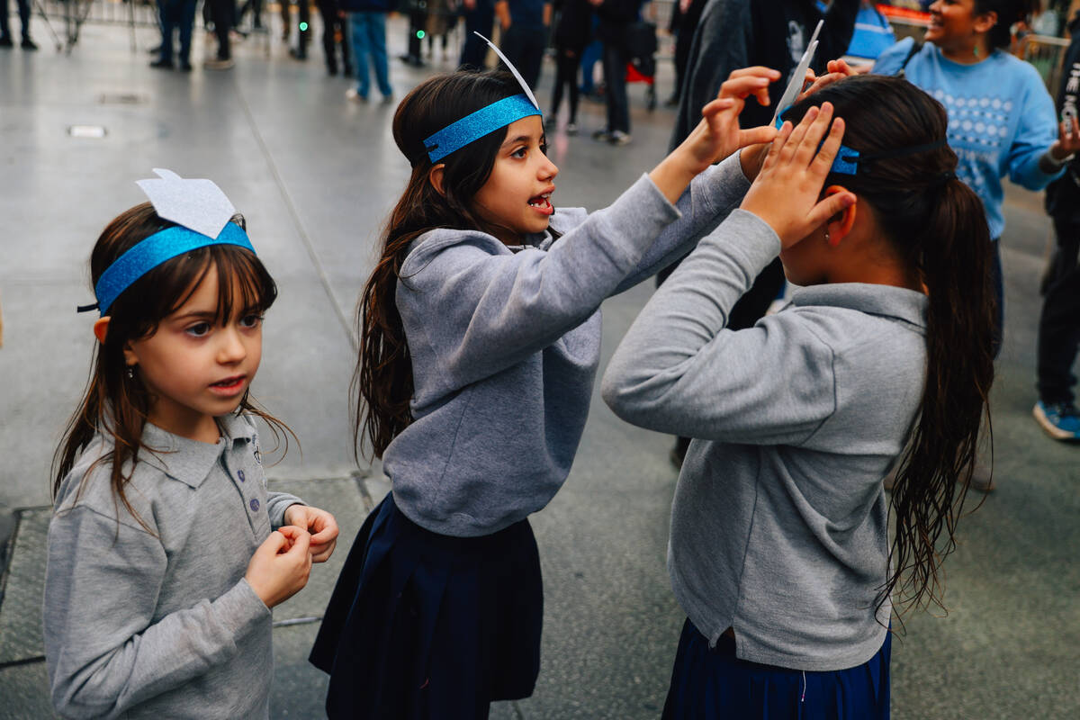 Children play with their headbands during the Fremont Street Experience menorah lighting Sunday ...