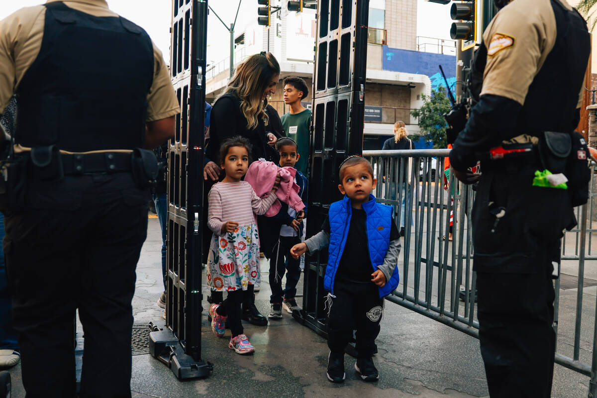 Attendees walk through a metal detector during the Fremont Street Experience menorah lighting S ...