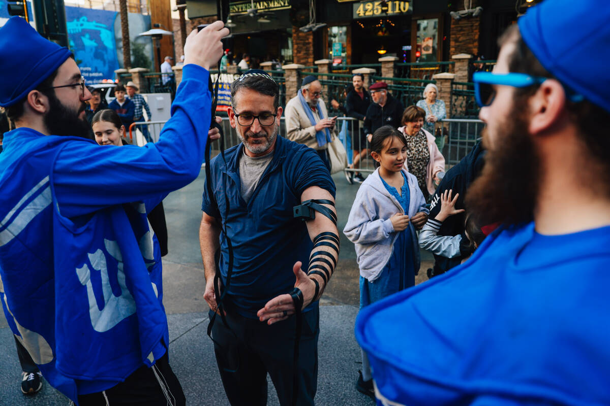 The tefillin is wrapped around an arm during the Fremont Street Experience menorah lighting Sun ...