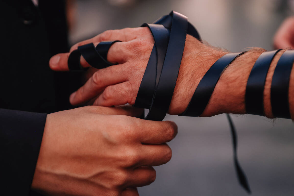 The tefillin is wrapped around an arm during the Fremont Street Experience menorah lighting Sun ...