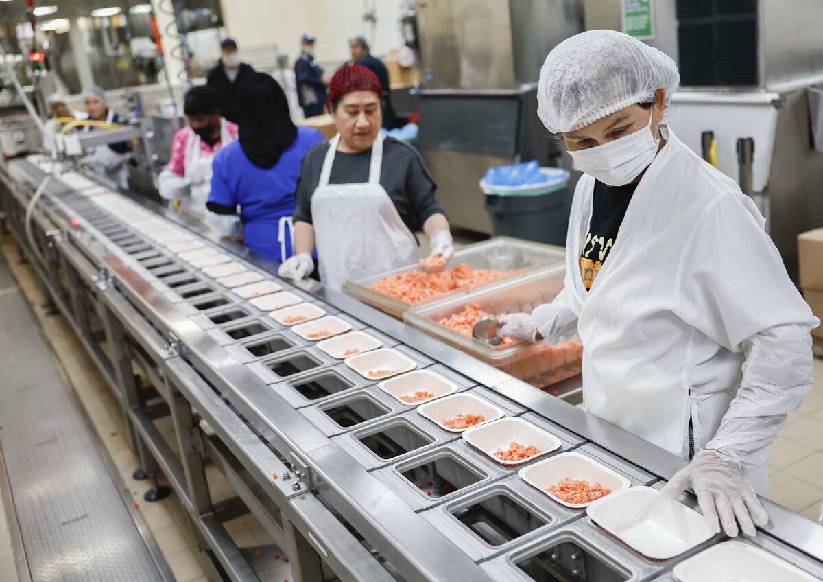 Food service workers fill trays on assembly lines at CCSD’s Central Kitchen Thursday, No ...