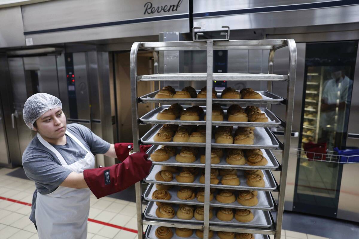 Food service workers move large trays of honey buns out of walk-in ovens at CCSD’s Centr ...