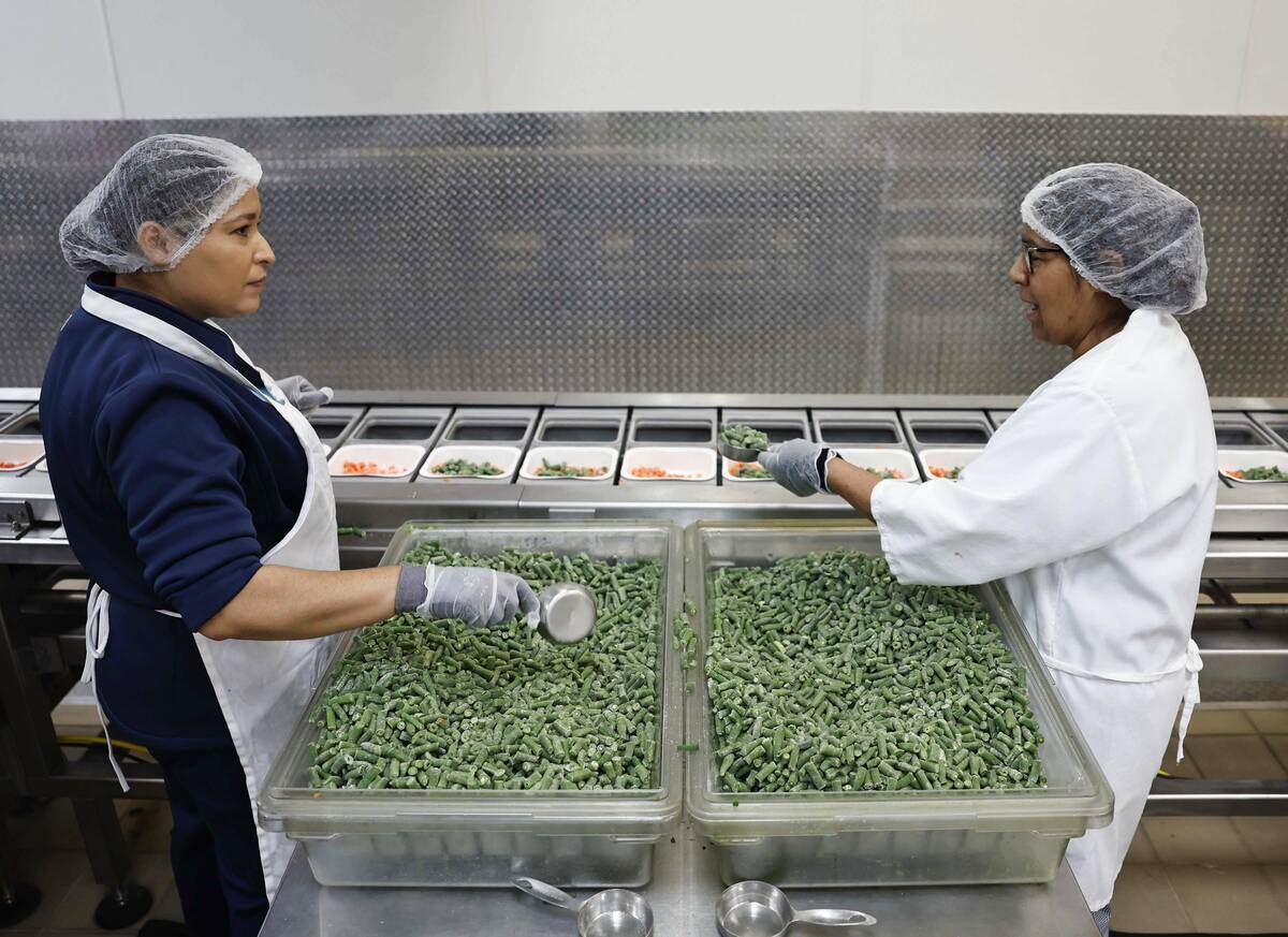 Food service workers add vegetables to trays on an assembly line at CCSD’s Central Kitch ...