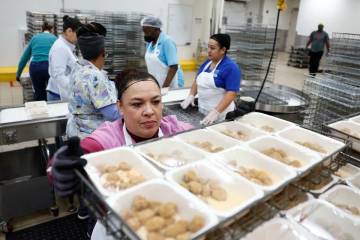 Food service workers pull completed trays off assembly lines at CCSD’s Central Kitchen T ...