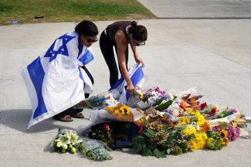 Women place flowers at a memorial outside Bondi Pavilion at Sydney's Bondi Beach, Monday, ...
