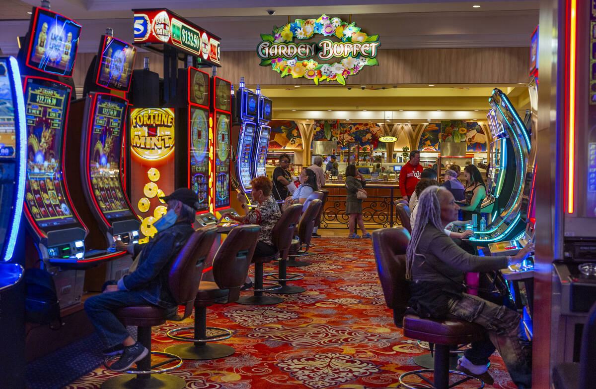 People play slots as others await a table in the Garden Buffet within the South Point on Friday ...