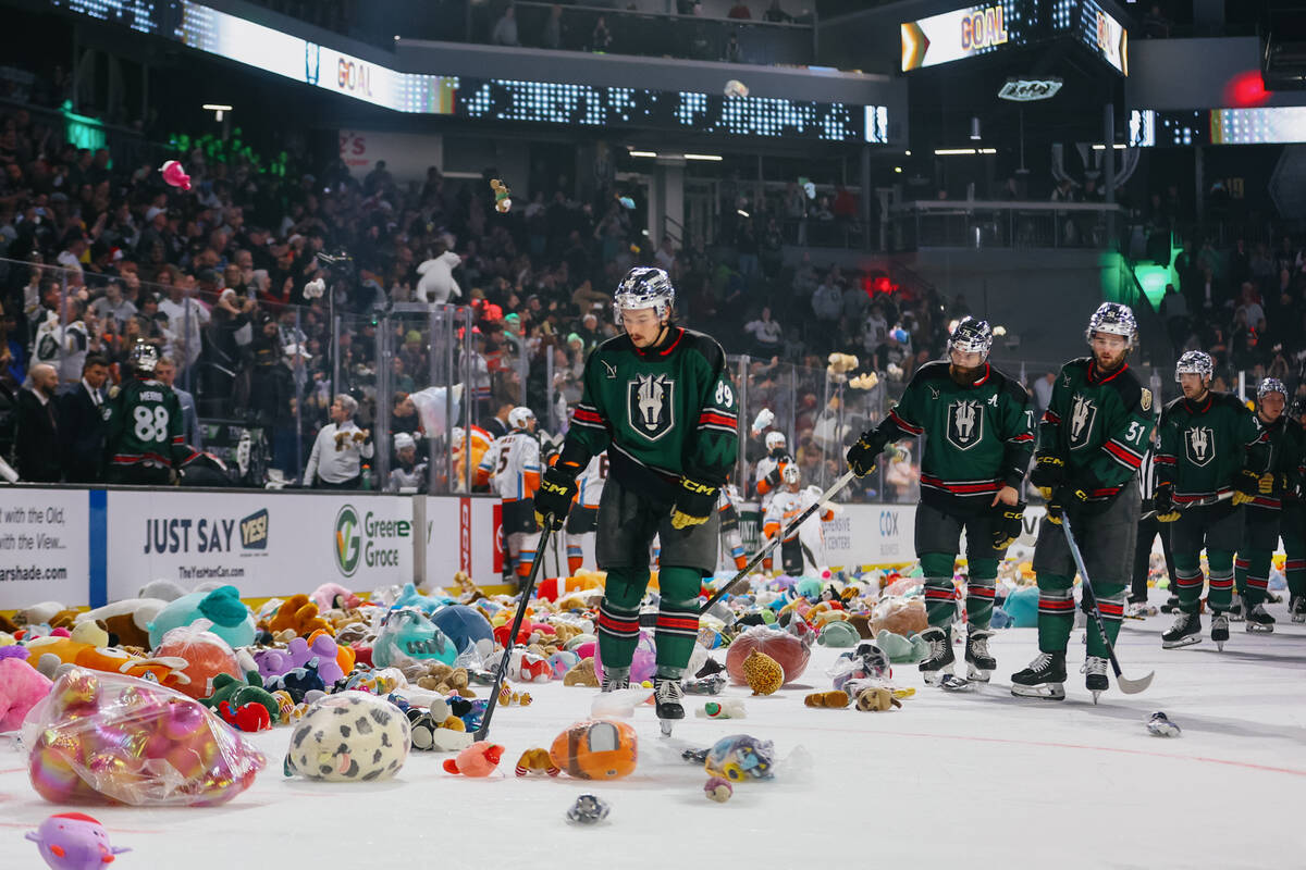 Silver Knights forward Riley McKay (89), center, starts to organize the piles of toys thrown on ...